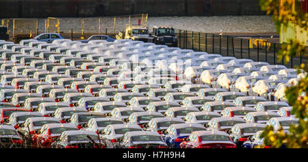 Cars waiting to be loaded at dock; New Luxury British made cars under wraps, wrapped for protection for export from the UK at Seaforth Docks.   White wrapped covered new British Jaguar & Land Rover made vehicles for export lining up on the Liverpool quayside for export.  CMA CGM  ship at Peel Ports £300m deep water container terminal, which can now handle the biggest container vessels in the world, Merseyside, UK Stock Photo