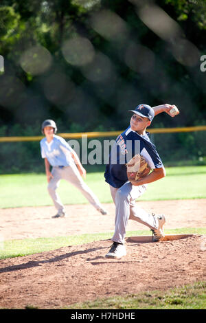 Teenage baseball player winding up for pitch to batter, opposition runner holding on 2nd base. St Paul Minnesota MN USA Stock Photo