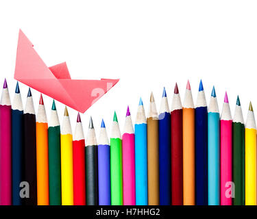A paper boat floating on a row of color pencils isolated on white with copy space Stock Photo