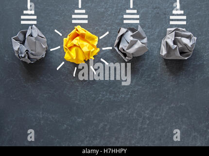 Bright orange light bulb made with paper against a grey lamps on a blackboard Stock Photo