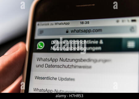 Hand holding iPhone displaying WhatsApp terms of service and privacy policy Stock Photo