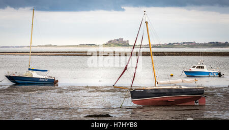 Bamburgh Castle with boat in foreground viewed from Lindisfarne Island, Northumberland, England, UK, GB, Europe. Stock Photo