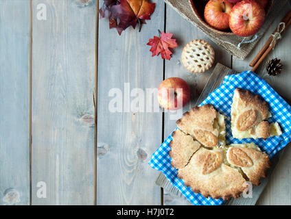 Apple pie with fruit ingredients autumn leaves and cinammon sticks on a wooden table Stock Photo