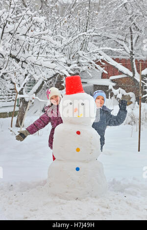 Happy children building snowman in garden Stock Photo