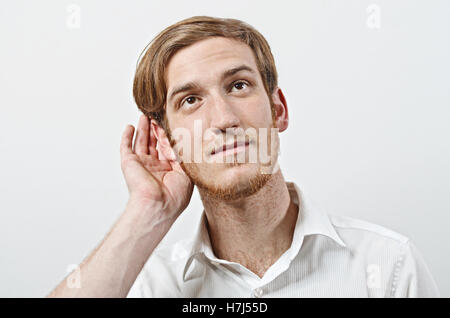 A Young Adult Male Wearing White Shirt with His Hand Near His Ear, Gestures Can Not Hear or Talk Louder Stock Photo