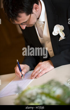 Civil wedding, groom signing a marriage certificate at the registry Stock Photo