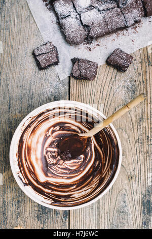 Empty mixing bowl, wooden spoon and homemade Chocolate brownies Stock Photo