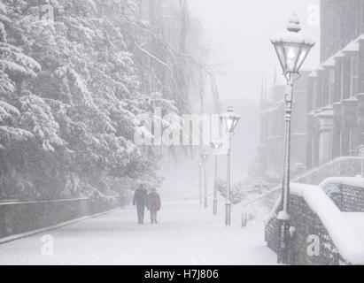 Buxton,Derbyshire in heavy snow. Two people walking on Broad Walk in the town centre Stock Photo