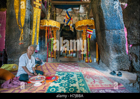 A monk offering blessings inside the main alter hall of Phnom Chisor, a Khmer temple in Cambodia Stock Photo