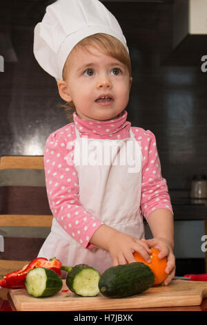 clouse-up portrait little cute girl. kid playing in the kitchen with vegetables Stock Photo