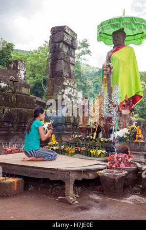 A devotee lays flowers at Wat Phu, a ruined Khmer Hindu temple complex in Champasak in southern Laos. Stock Photo