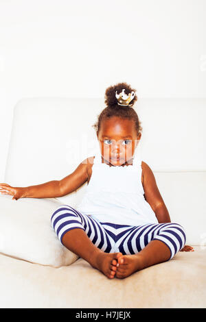 little pretty african american girl sitting in white chair weari Stock Photo