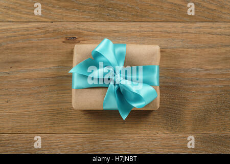 brown gift box with light blue ribbon bow on wooden oak table from above Stock Photo
