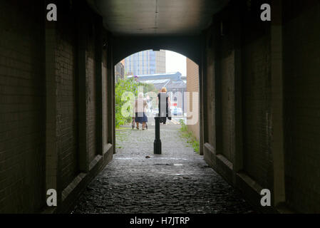 Old invalid  with walking aid and man through tunnel Stock Photo