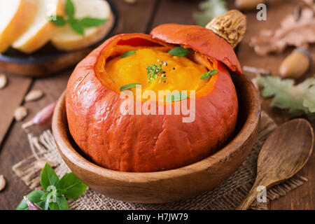 Pumpkin cream soup with peppers and herbs in a pumpkin. Stock Photo