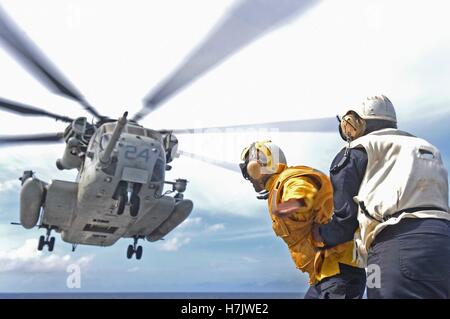 U.S. soldiers signal as a CH-53E Super Stallion helicopter launches from the flight deck of the USN Whidbey Island-class amphibious dock landing ship USS Ashland August 17, 2014 in the Pacific Ocean. Stock Photo