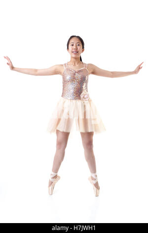 Young Asian ballerina with braces executing a ballet pointe movement. Isolated on white background. Stock Photo