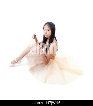 Young and beautiful Asian ballerina tying her ballet pointe shoes. Isolated on white background. Stock Photo
