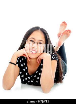 Asian tween girl lying on floor in confident pose, isolated on white background