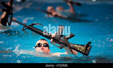 U.S. Marines perform a rifle swim during Marine Corps Instructor of Water Survival Course aquatic conditioning at the Marine Corps Base Camp Gilbert H. Johnson March 6, 2013 in Jacksonville, North Carolina. Stock Photo
