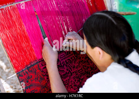 Native Peruvian woman weaving intricate llama wool garments using a traditional hand loom Stock Photo