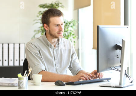 Concentrated businessman working on line typing in a desktop computer at office Stock Photo