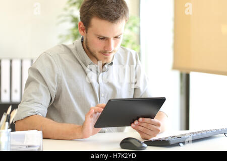 Entrepreneur working on line with a tablet sitting in a desk at office Stock Photo