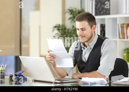 Happy businessman reading a letter sitting in a desk at office Stock Photo