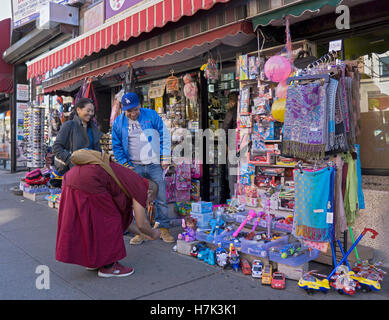 A Tibetan monk taking cell phone photos of a singing wind up doll on 37th Ave in Jackson Heights, Queens, New York City, Stock Photo