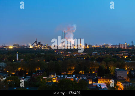 View of a large coking and steel plant in Duisburg, Germany in the night with coke quenching producing steam. Stock Photo