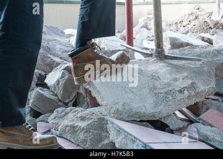 Bricklayer with pickaxe, rebuilding waterproofing and insulation of a terrace, excavation Stock Photo