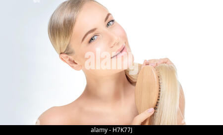 Portrait of a beautiful blond woman combing her perfect straight hair over clear background, fashion model Stock Photo