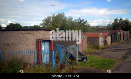 Dilapidated run down sheds still in use with airplane in sky Stock Photo