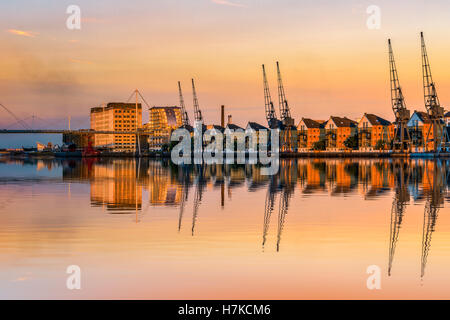 Royal Victoria Dock in London at sunset with dockside cranes and waterfront terraced houses Stock Photo