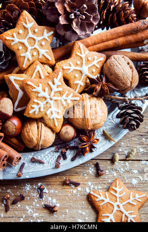 Christmas decor with homemade gingerbread cookies stars, cones, nuts and Christmas spices over rustic wooden background