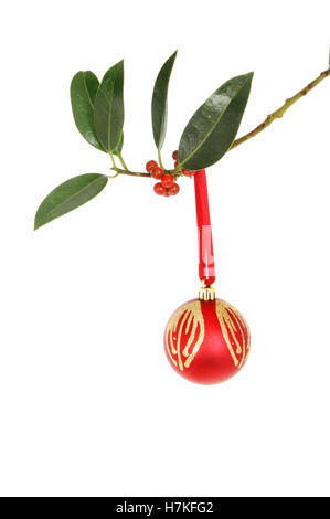 Red and gold glitter Christmas bauble hanging from a Holly branch Stock Photo