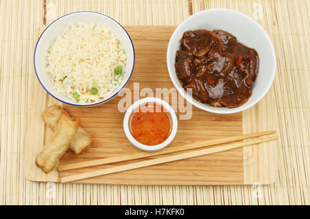 Chinese food, rice, beef in black bean sauce and spring rolls on a bambo matt Stock Photo