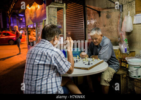 Two older men, playing chess on the streets of Bangkok Stock Photo