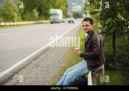 Man sitting on a road fence with gps tablet pc and using online maps Stock Photo
