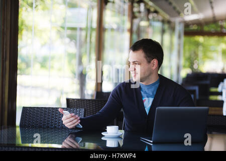Young fashion man hipster drinking espresso coffee in the city cafe during lunch time and working on tablet computer Stock Photo
