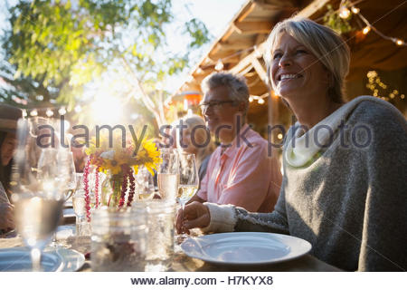 Smiling woman enjoying sunny harvest dinner party