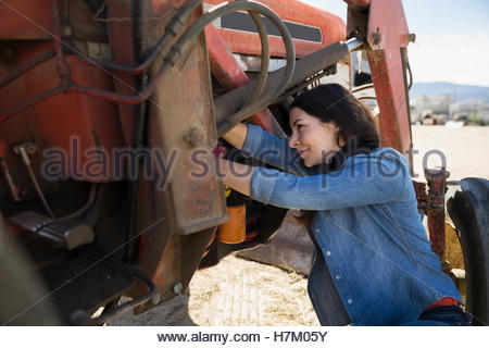 Female mechanic repairing tractor on farm