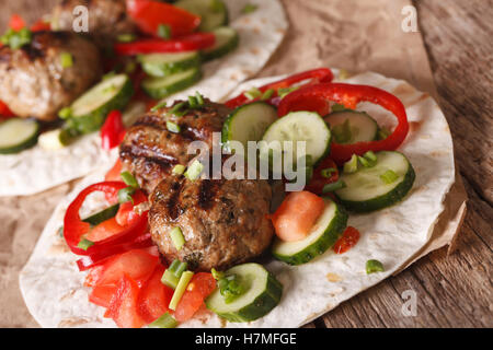 Arabian food: meat balls with fresh vegetables on a flat bread close up on the table. horizontal Stock Photo