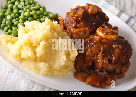 Salisbury steak with mashed potatoes and green peas close-up on a plate on the table. horizontal Stock Photo