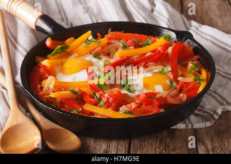 Tasty Piperade: fried eggs with peppers and tomatoes close up in a pan. horizontal Stock Photo
