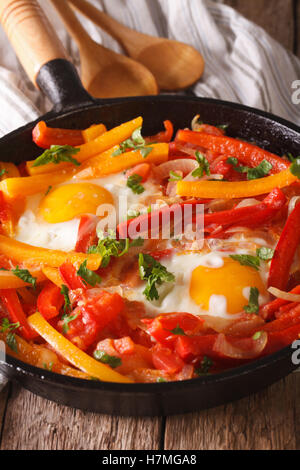 A delicious breakfast: fried eggs with peppers in a pan close-up. Vertical Stock Photo