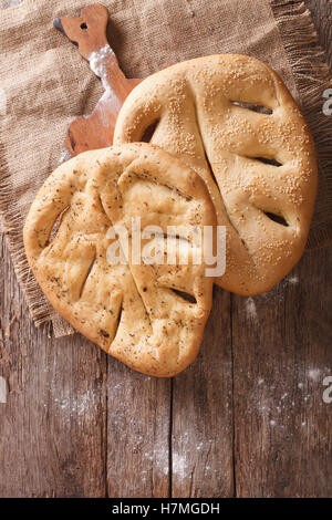 Fugasse French bread with sesame seeds and herbs closeup on the table. Vertical view from above, rustic Stock Photo