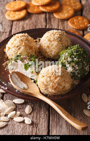 Cottage cheese balls with crackers, herbs and pumpkin seeds close-up on a plate. vertical Stock Photo