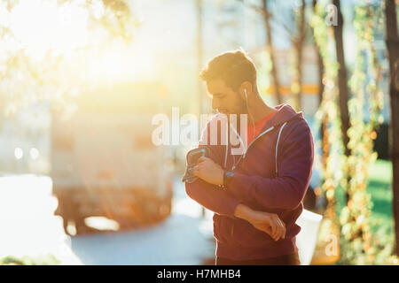 runner listening to music adjusting settings on armband for smartphone Stock Photo