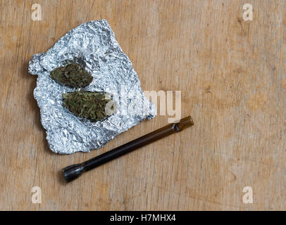 Marijuana in tin foil with pipe on wooden table Stock Photo - Alamy